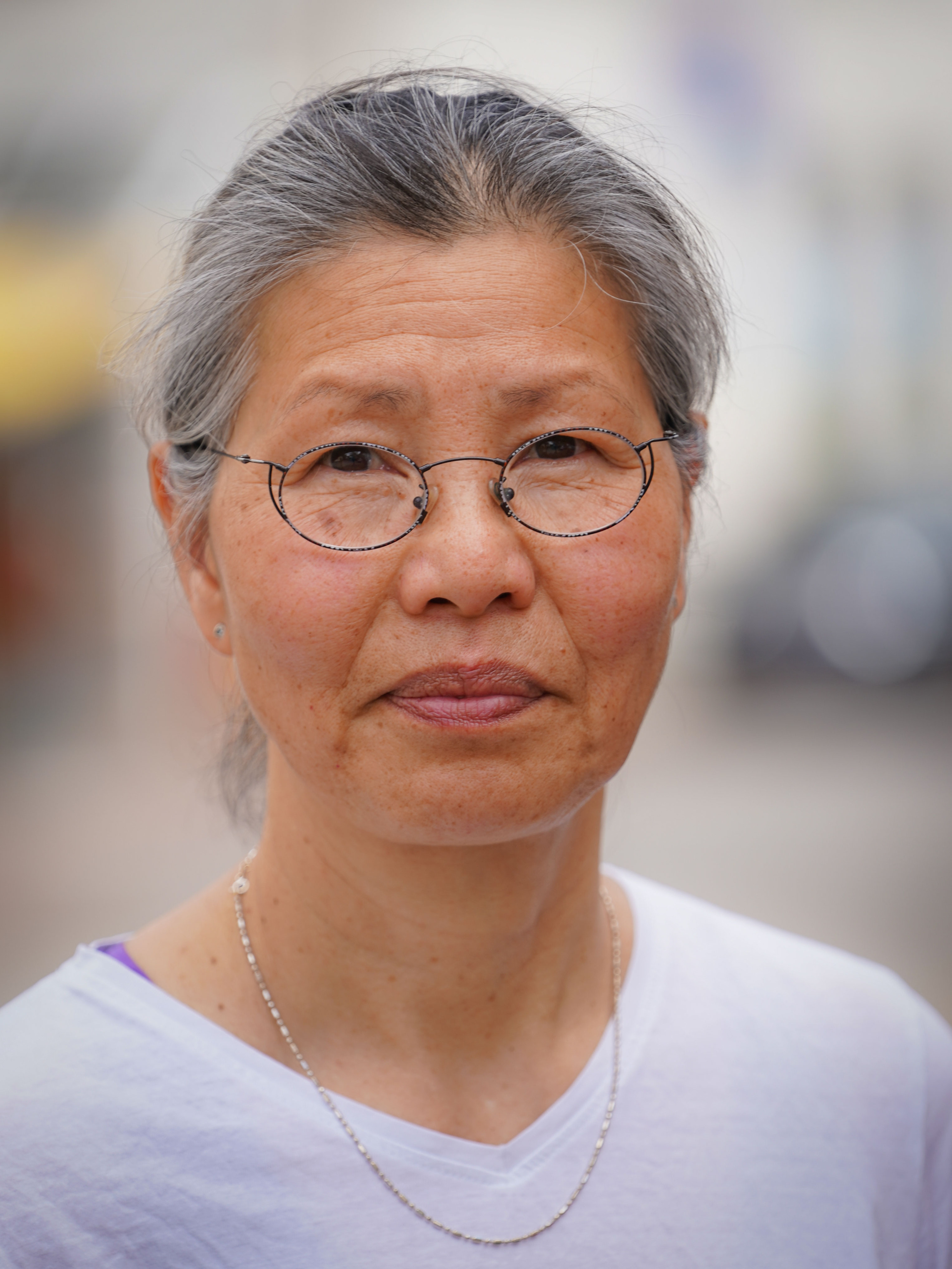 Porträtfoto von Evelyn Vonbun mit grauem Haar und Brille, im Hintergrund unscharf eine Straßenszene