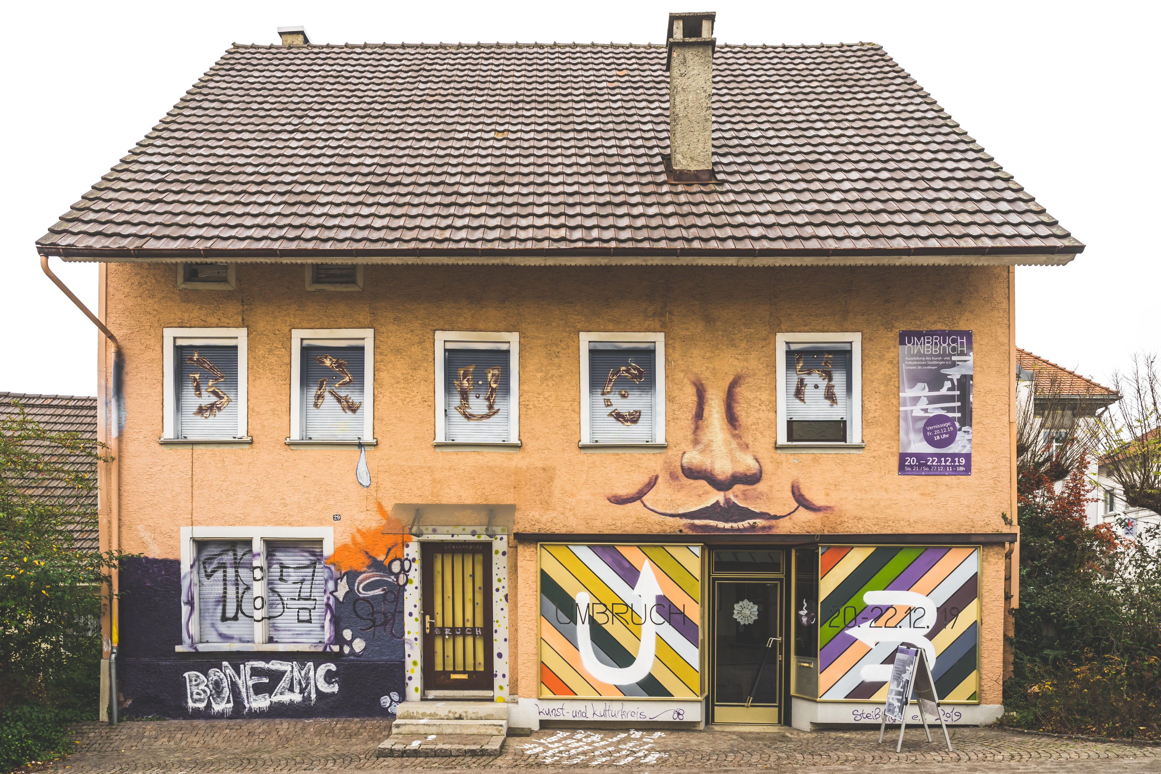 Gelbes Haus mit bemalten Fensterläden und Graffiti an der Fassade