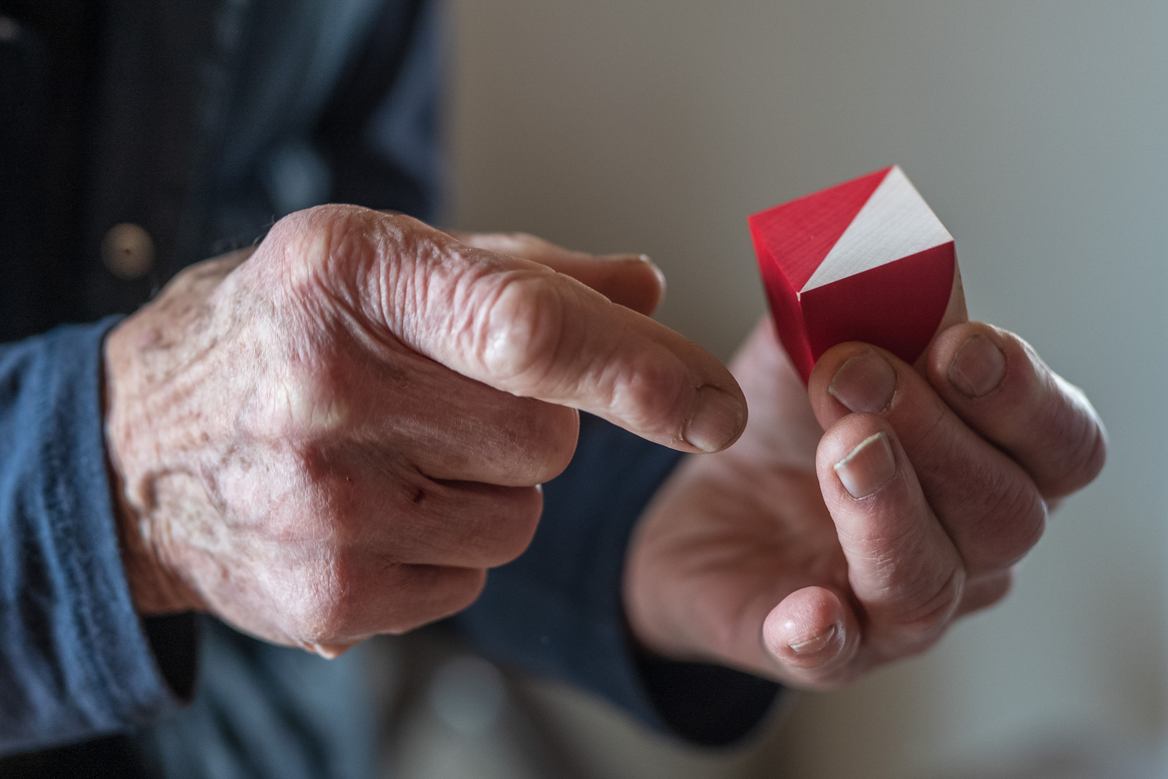 Zwei Hände halten ein rot-weißes dreieckiges Objekt