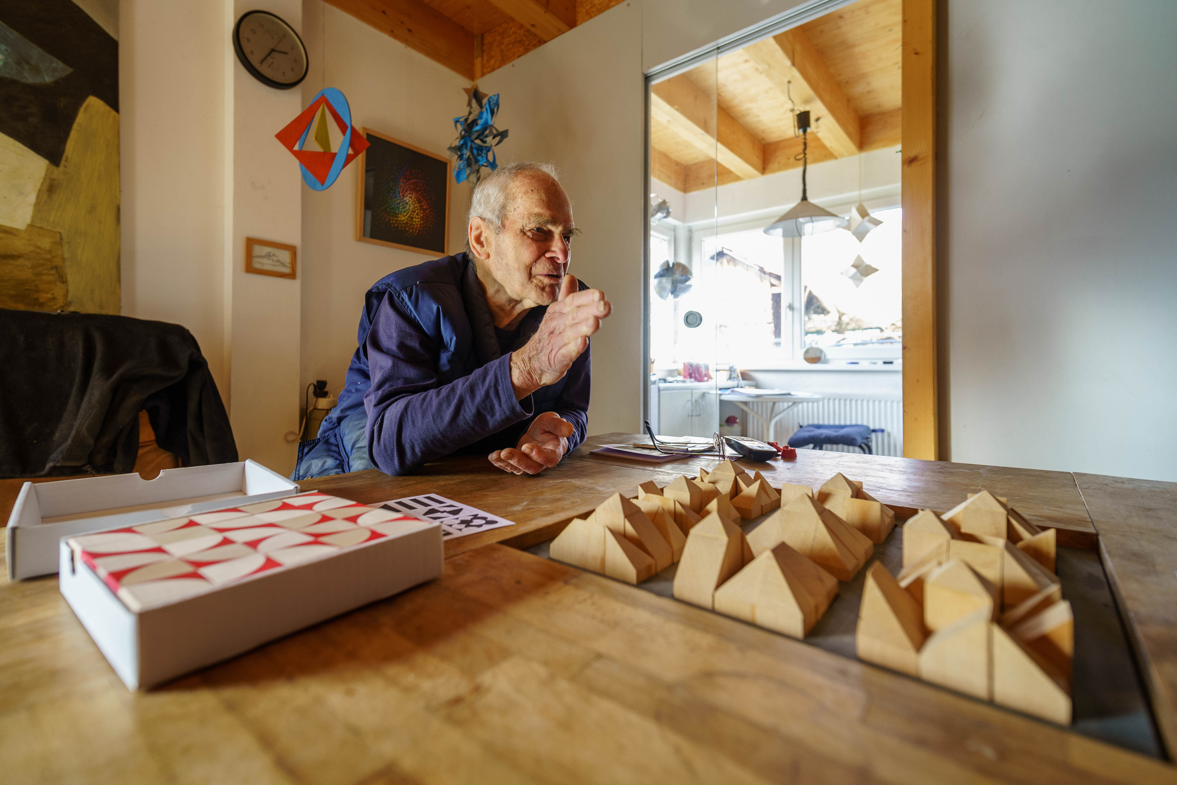 Der Künstler vor einem Modell aus dreieckigen Holzformen