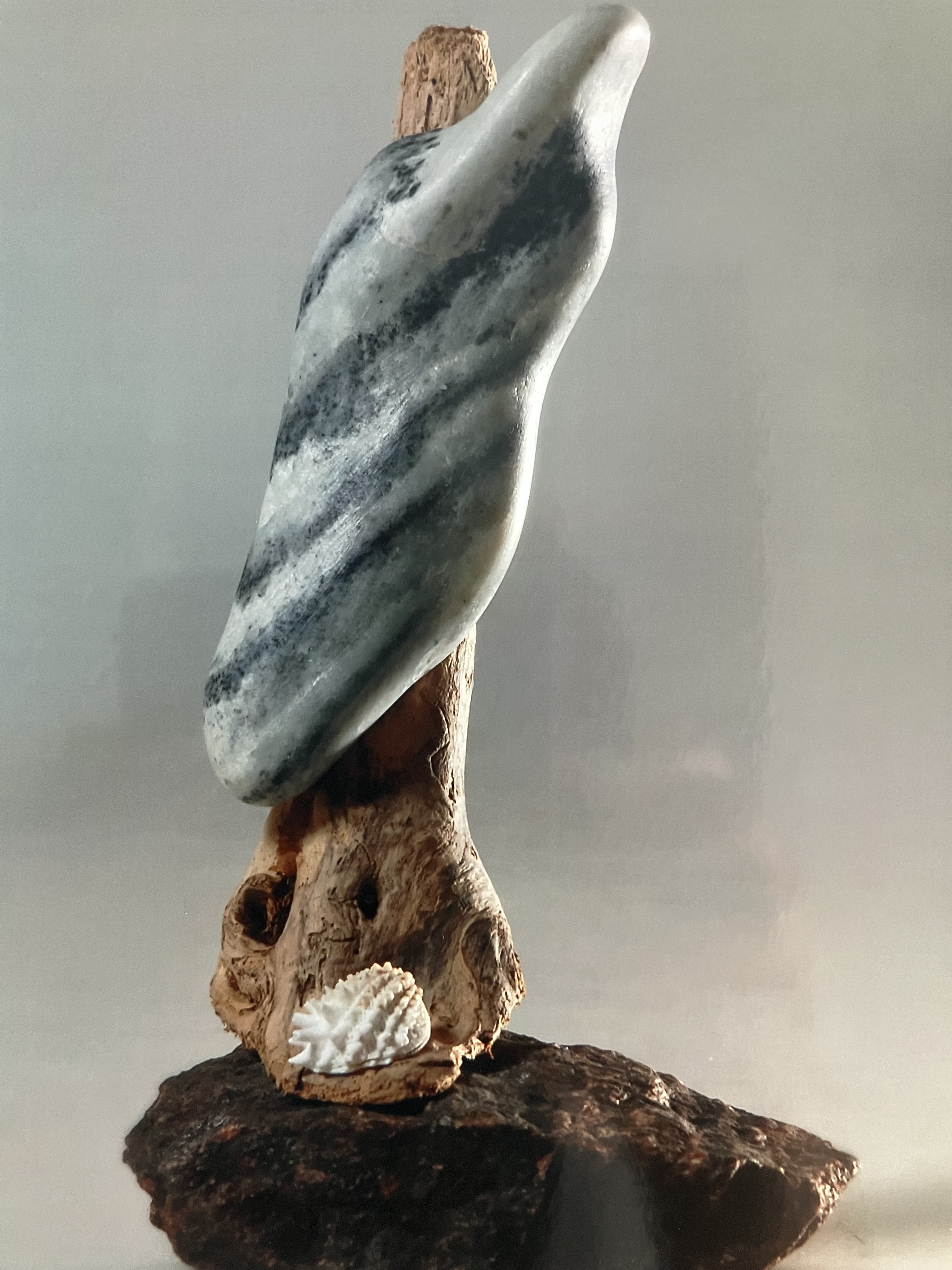 Geschwungene, flügelartige Speckstein-Skulptur in Grau-Weiß-Streifen auf einem Sockel aus Treibholz