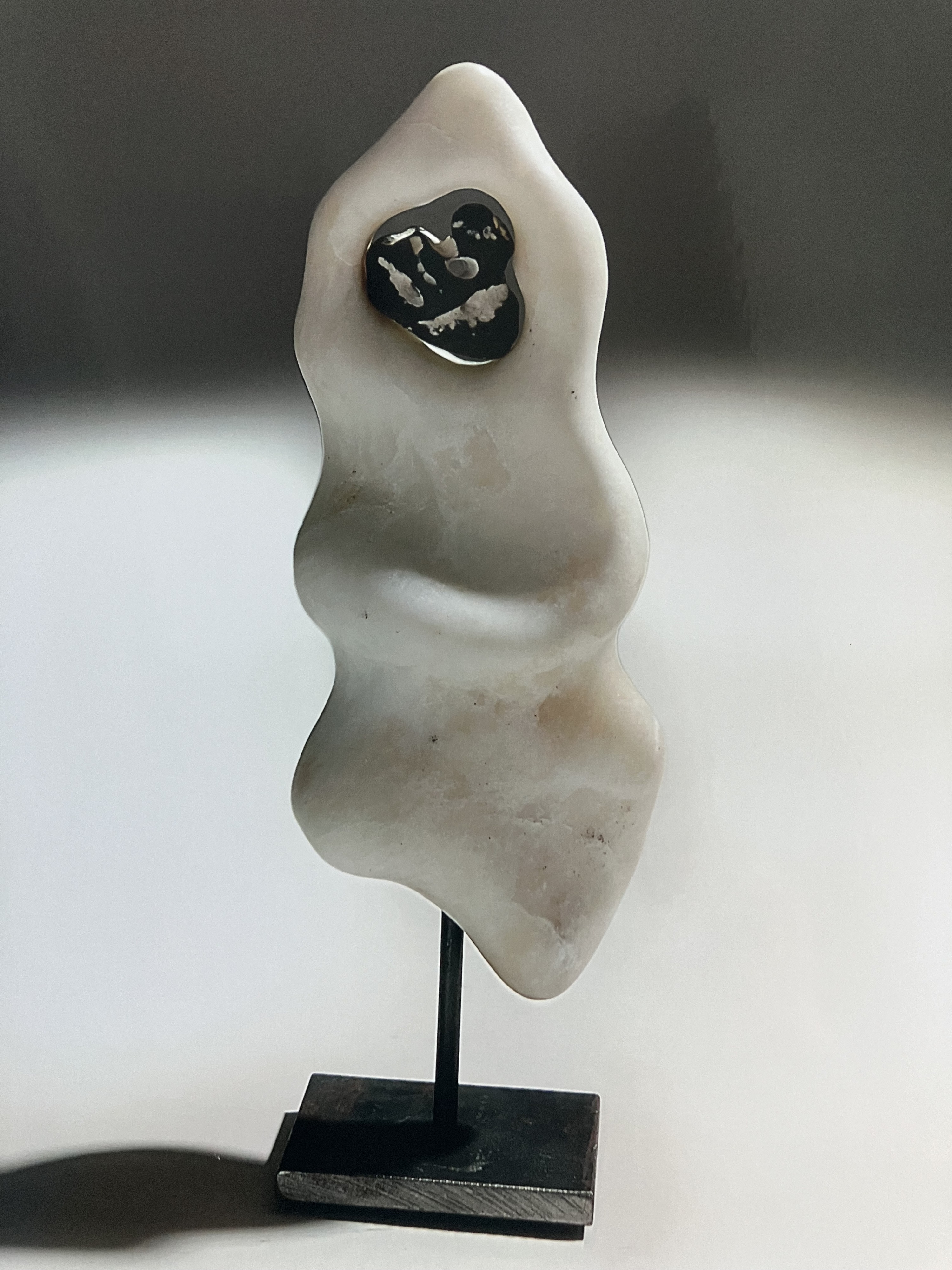 Wellenförmige Speckstein-Skulptur in Cremeweiß mit schwarzem Einsatz, auf schwarzem Metallsockel