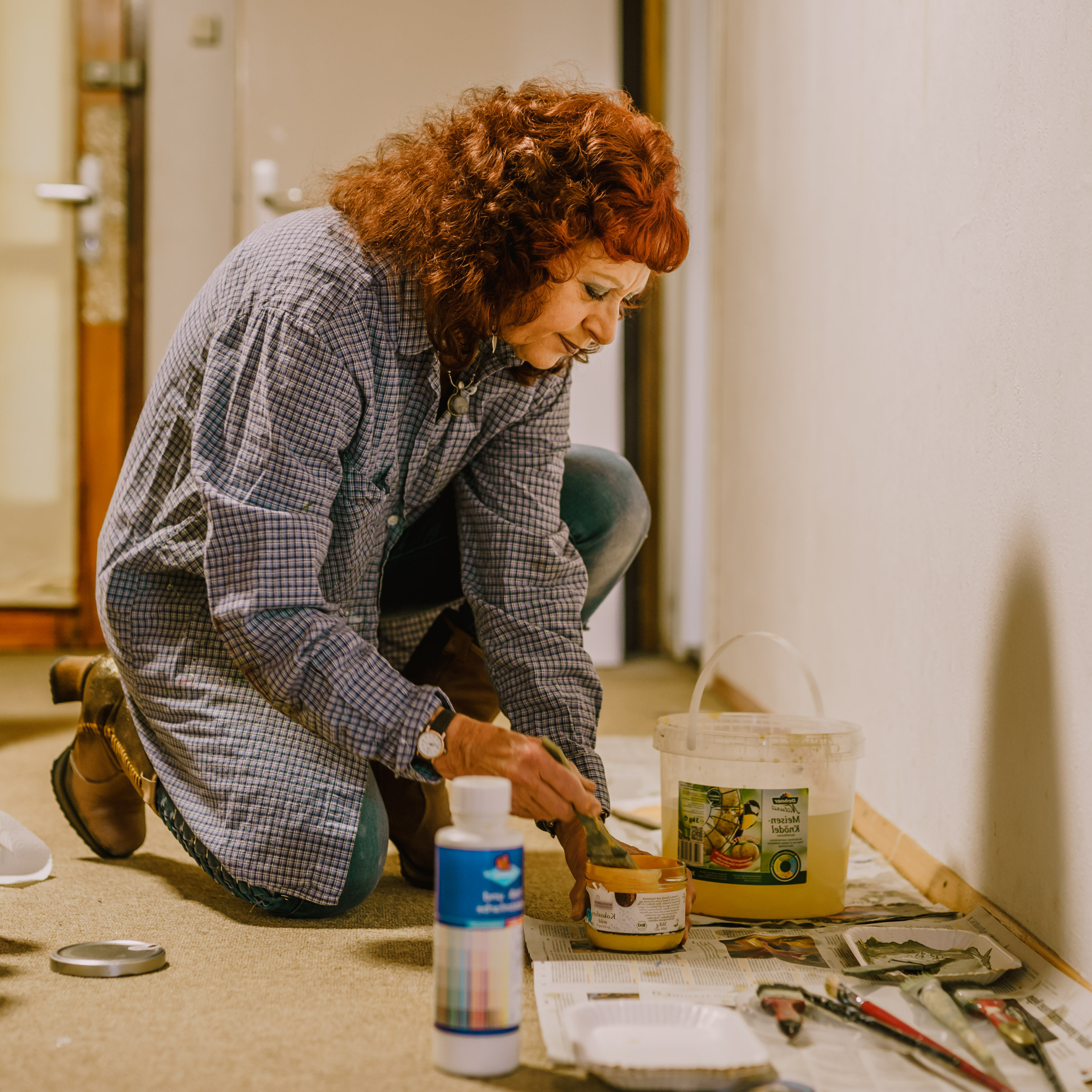 Sarah Hiener kniend beim Malen auf dem Boden ihres Ateliers