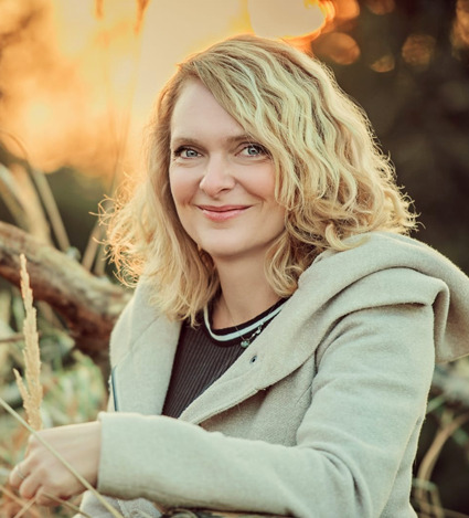 Porträt von Steffi Bergmann, lächelnd im Gegenlicht vor herbstlichem Hintergrund