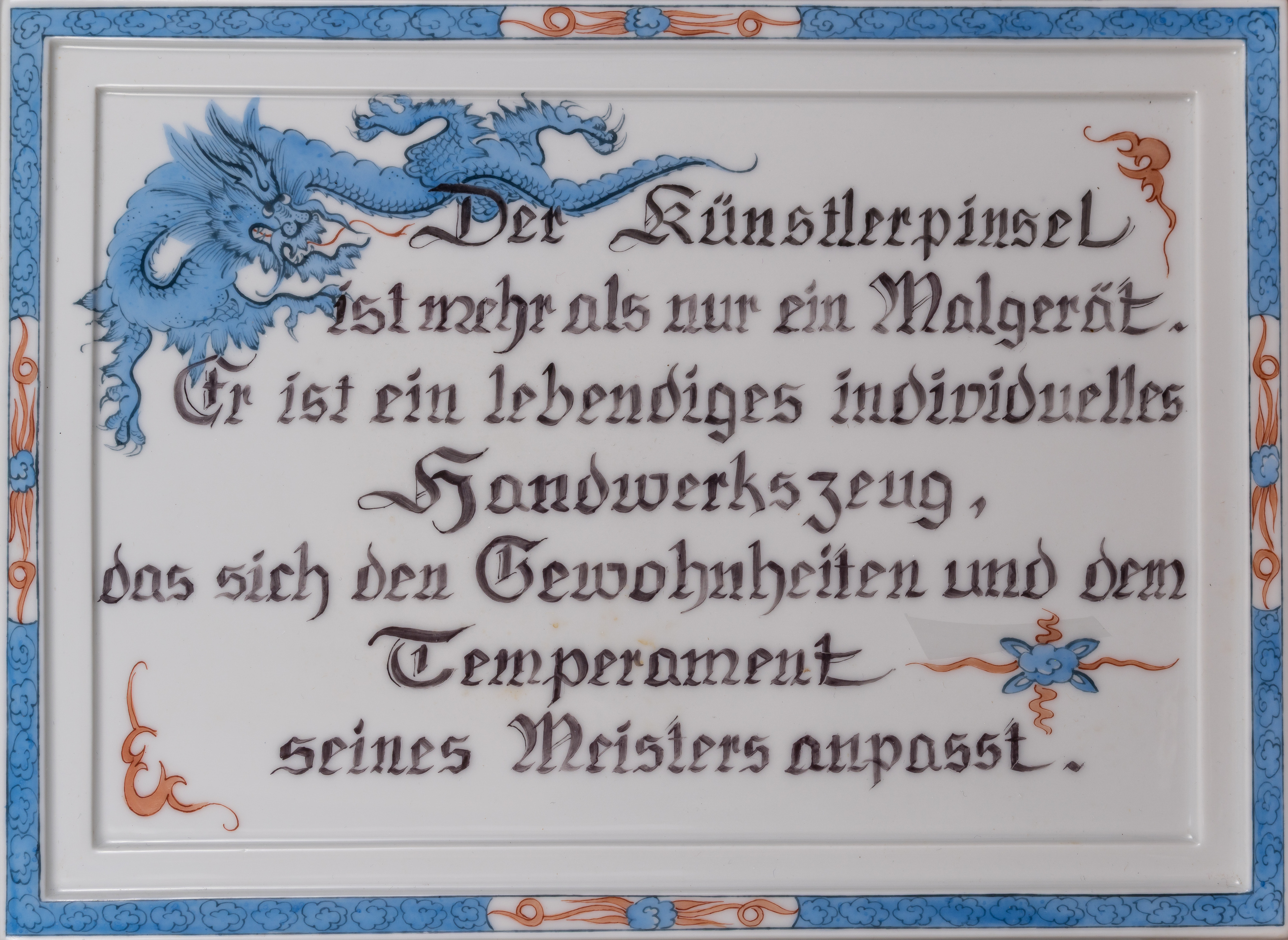 Weiße Keramikplatte mit blauem Rahmenmuster und blauem Drachen, beschriftet mit kalligrafischem Zitat über den Künstlerpinsel