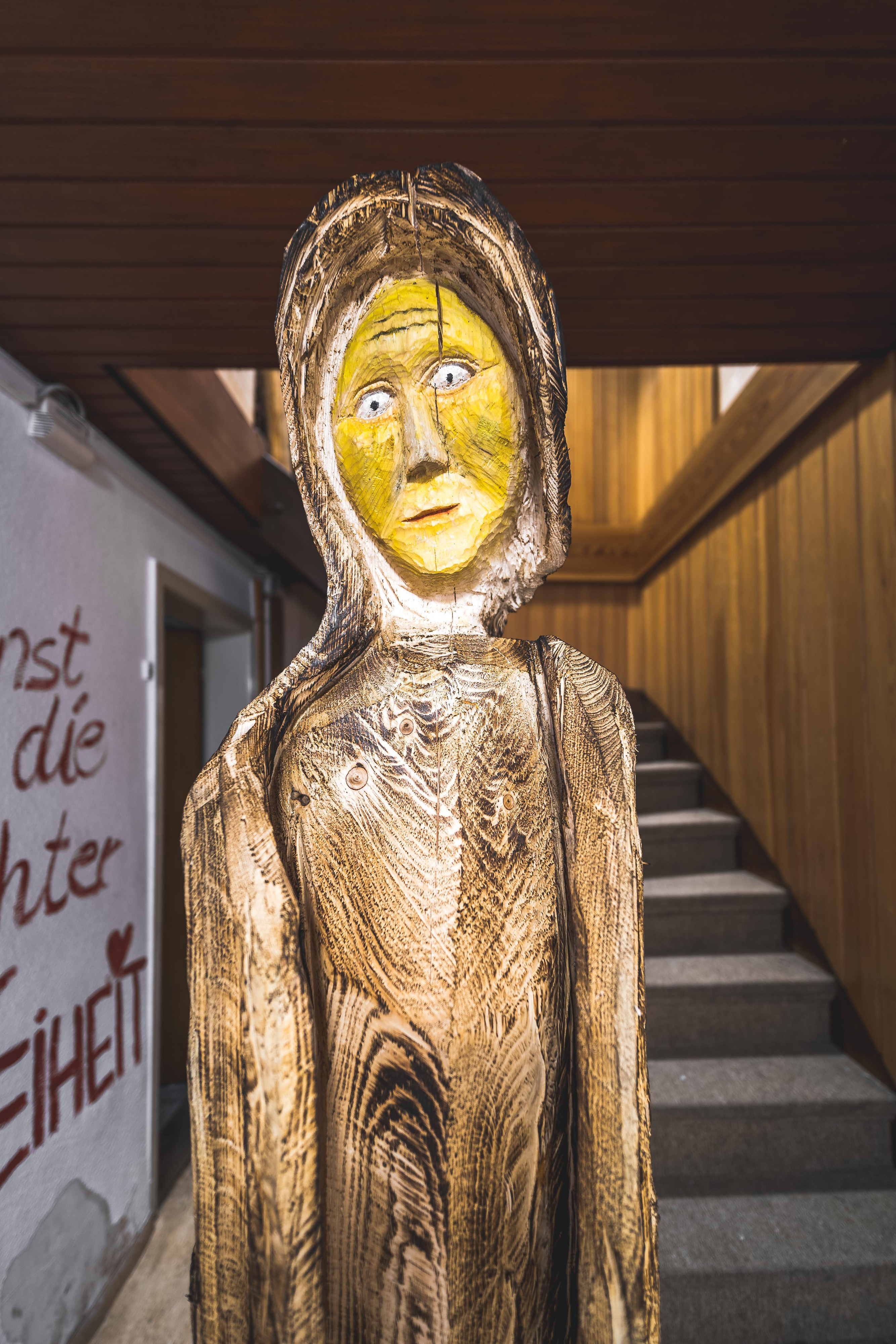 Stehende geschnitzte Holzfigur mit gelb gefasstem Gesicht