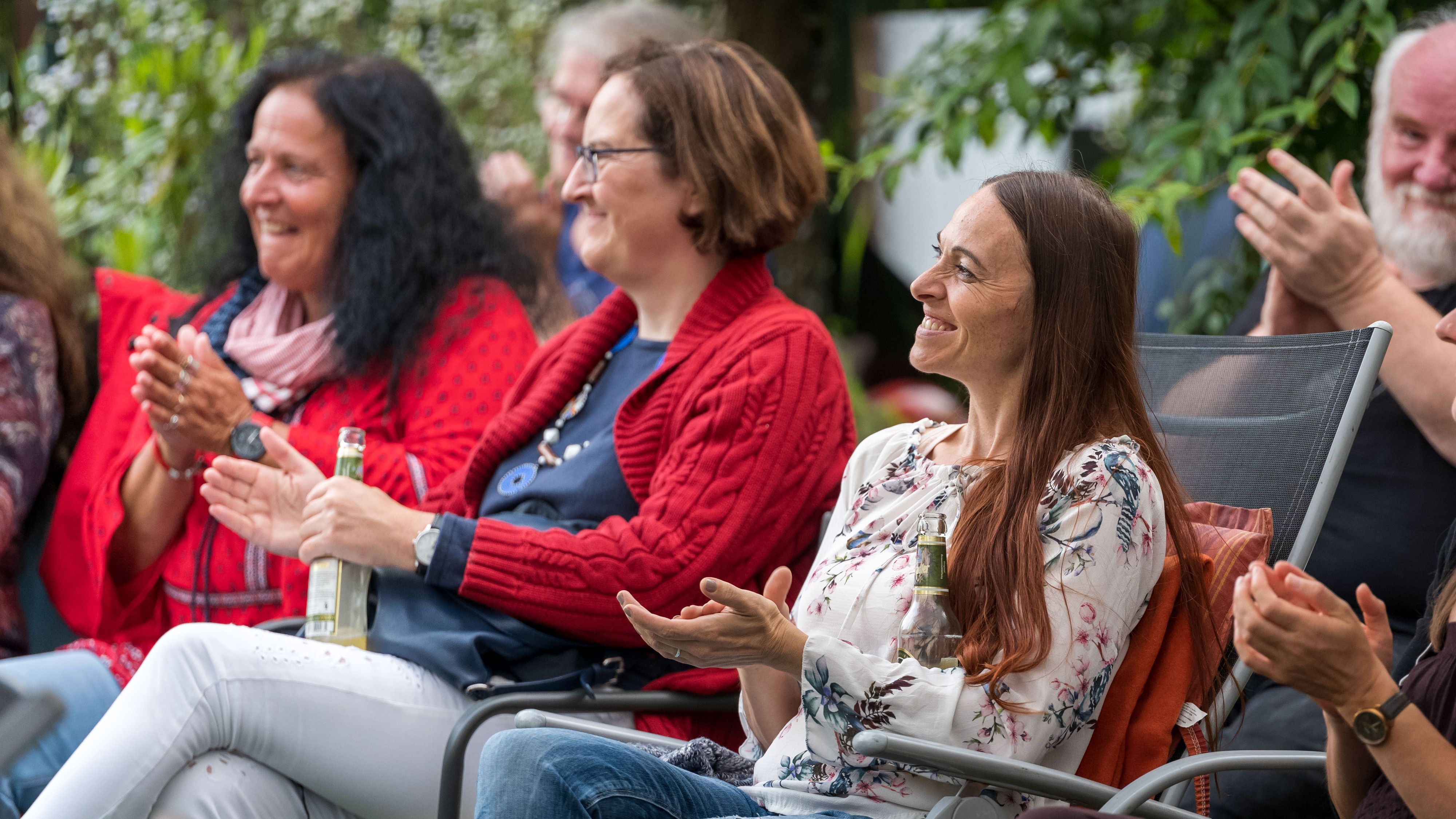 Publikum sitzt im Garten und applaudiert