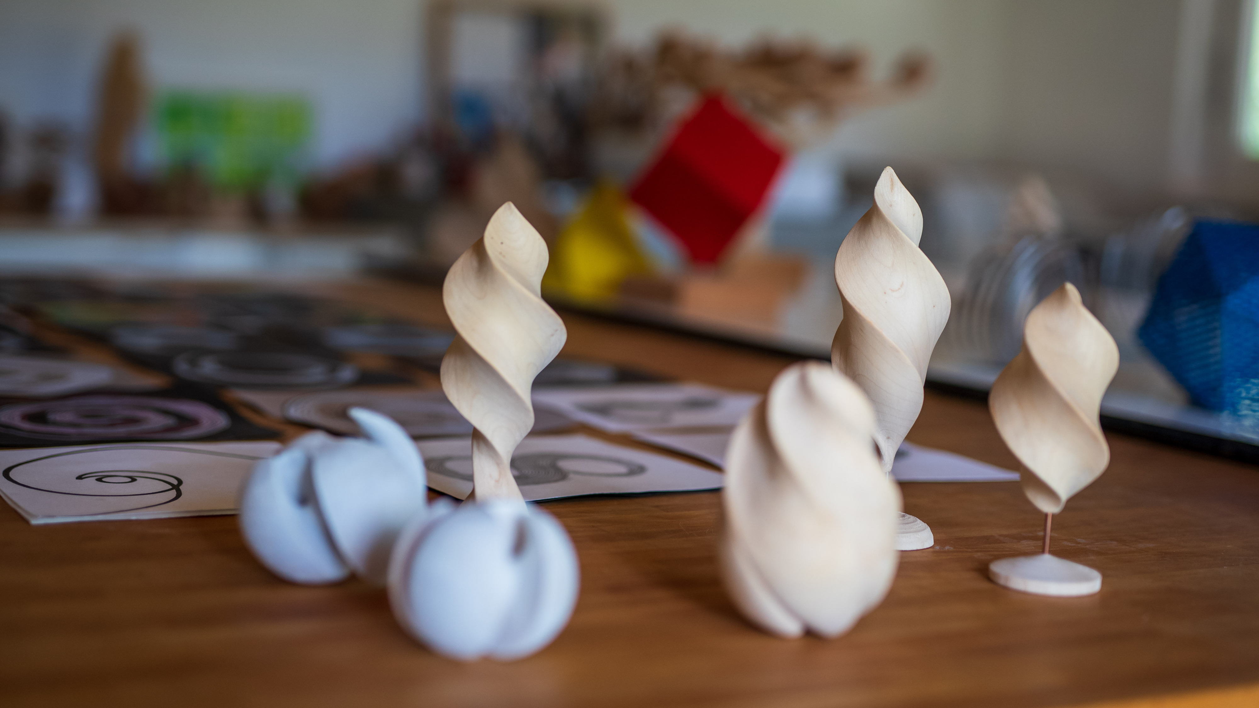 Mehrere weiße, gedrehte Gipsspiralen und -kegel auf einem Holztisch