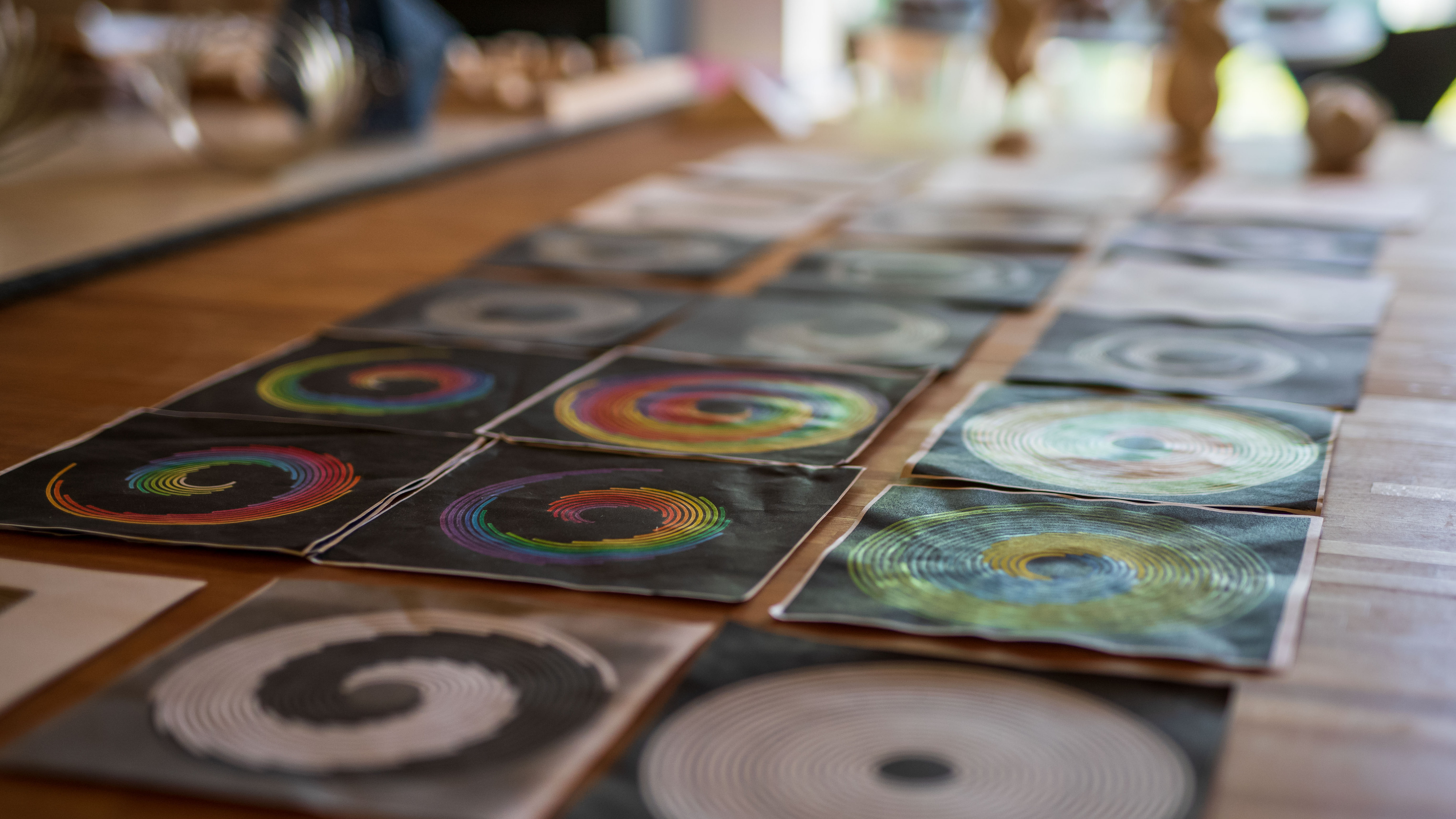 Runde Spiralbilder in Schwarz-Weiß und Farbe, dicht an dicht auf einem Tisch