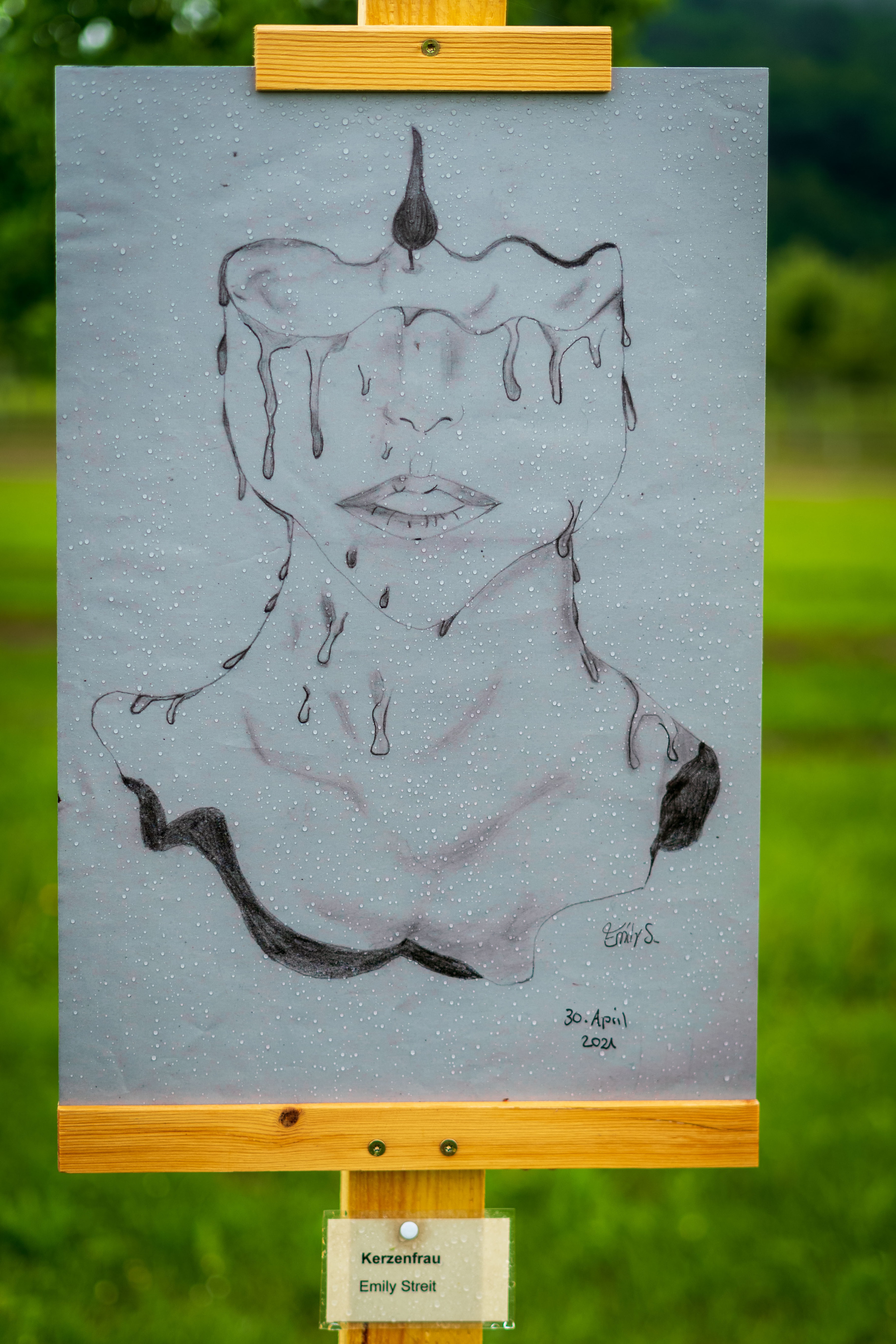 Kohlezeichnung einer stilisierten Figur mit Krone auf Papier, auf einer Staffelei