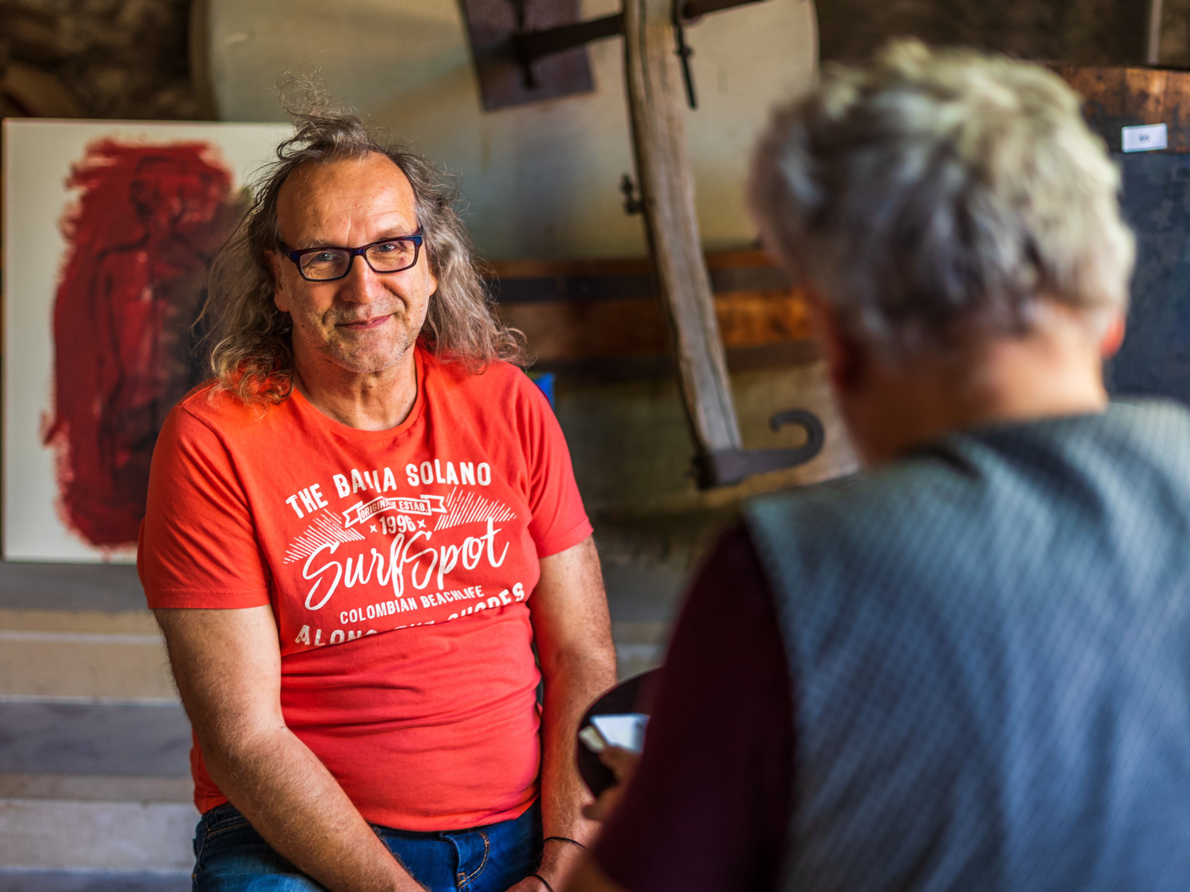 Ein Mann im roten T-Shirt unterhält sich mit einer Frau mit grauen Haaren